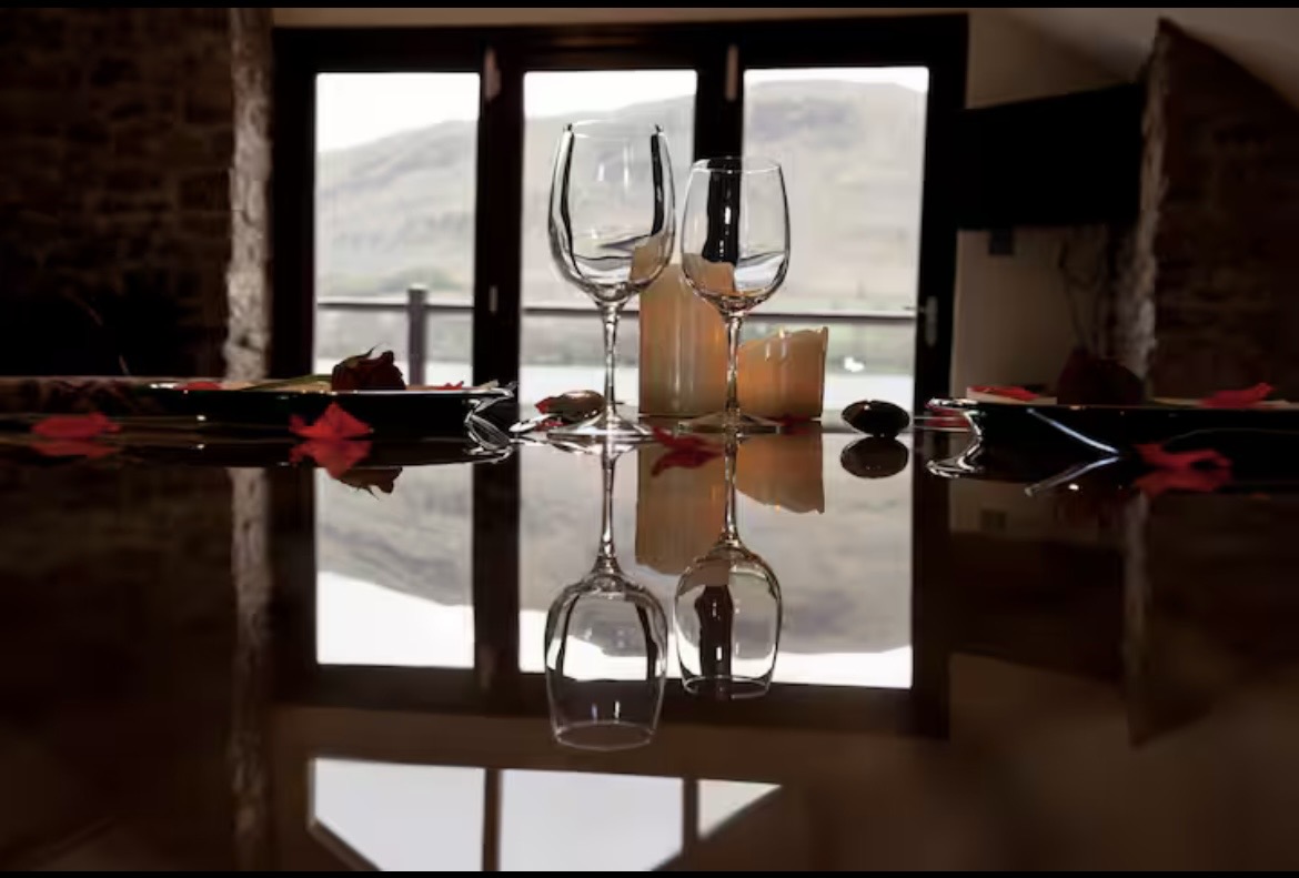 Wine glasses and candle on a polished dining table with Lake District views