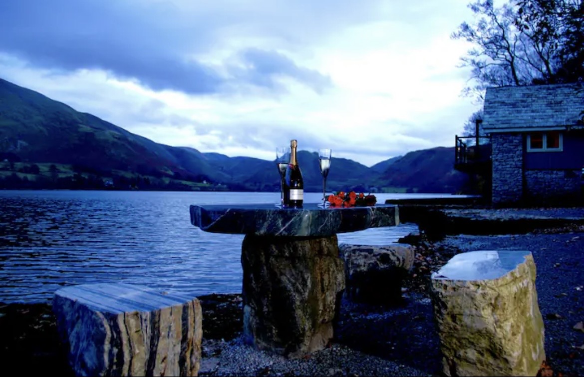 Champagne and glasses on a stone table by the lake at dusk
