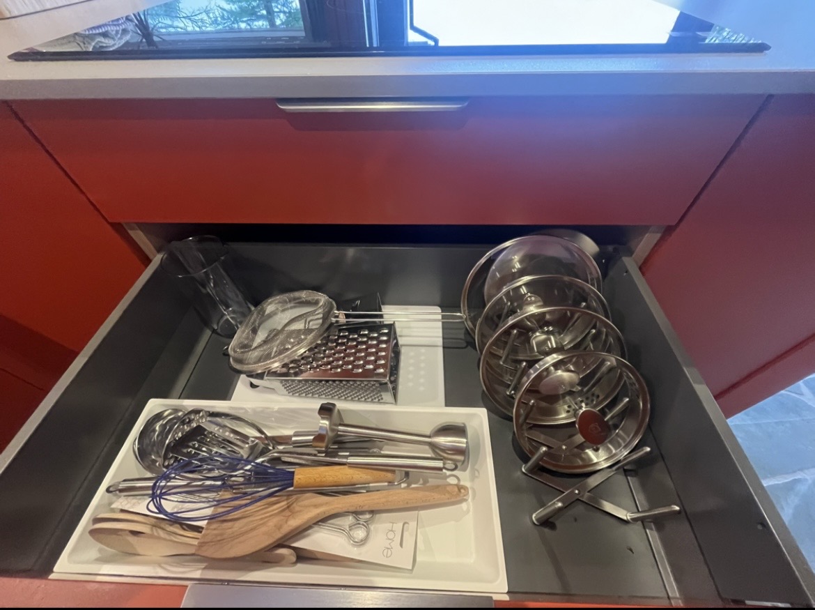 Neatly organised kitchen drawer with utensils and pan lids after a deep clean